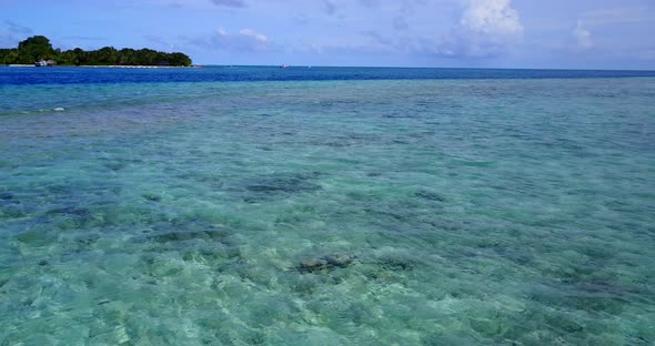 Wide flying copy space shot of a white paradise beach and turquoise sea background in vibrant 4K