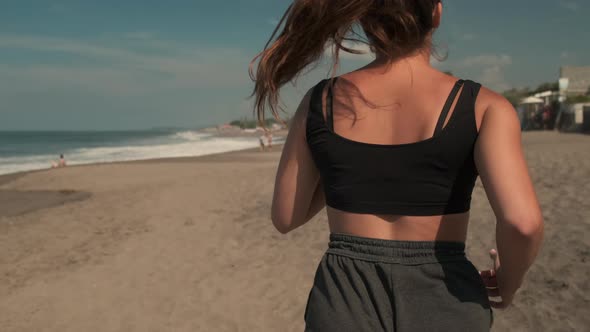 Sportswoman Running Along Sandy Coastline