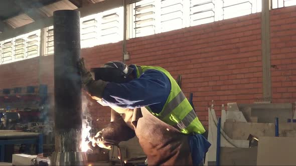 Worker welding a metal peace in an industrial space. Slow motion.