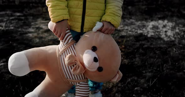 Orphan Child in the Colors of the Ukrainian Flag with a Toy Bear in Ukraine War