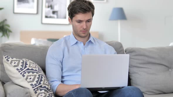 Handsome Young Man Working On Laptop While Sitting on Couch