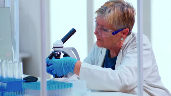 Senior Woman Scientist Doing Investigation Using Microscope