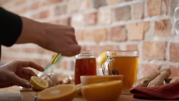 Hands of unrecognizable woman cutting lemon for winter tea. Shot with RED helium camera in 8K.