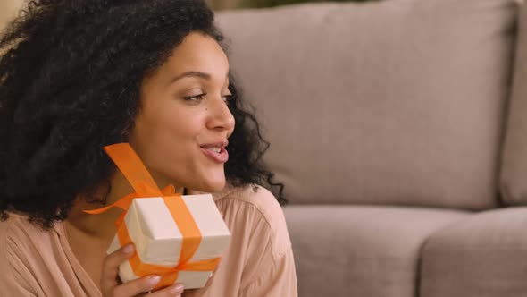 Afro American Woman Gives Gift Box to an Enthusiastic and Surprised Little Girl