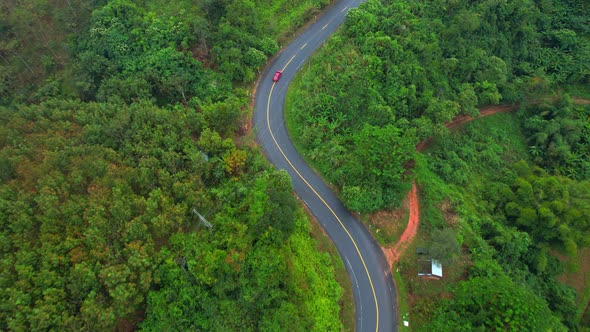 Aerial view over a winding road in the mountains of a tropical forest, Thailand.