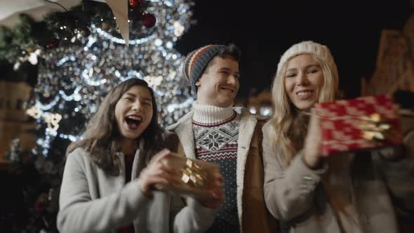 Happy Friends Dancing with Gifts in Hands at Xmas Night at Old Town Square