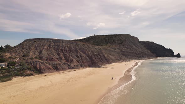 People strolling by the sea. Sand beach of Praia Da Luz, Algarve. Tranquility and peacefulness