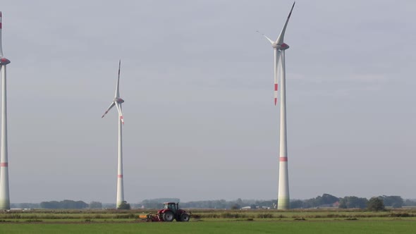 A Tractor ploughing a field with Wind Turbines in the background. East Frisia. Lower Saxony. Germany