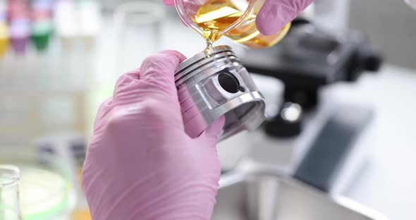 Scientist in Rubber Pink Gloves Holds Automotive Part and Pours Lubricating Oil