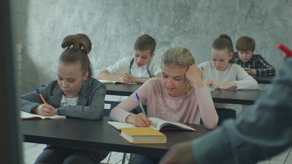 Children writing notes in class during lesson