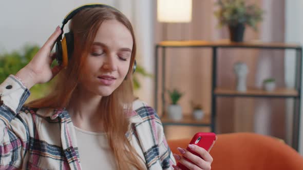 Pretty Caucasian Young Woman in Headphones Listening Music Dancing Singing in Living Room at Home