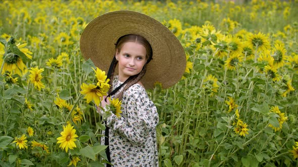 Beautiful Smiling Teen Girl in Wicker Hat Posing in Sunflower Field