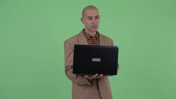 Serious Bald Multi Ethnic Businessman Thinking While Using Laptop