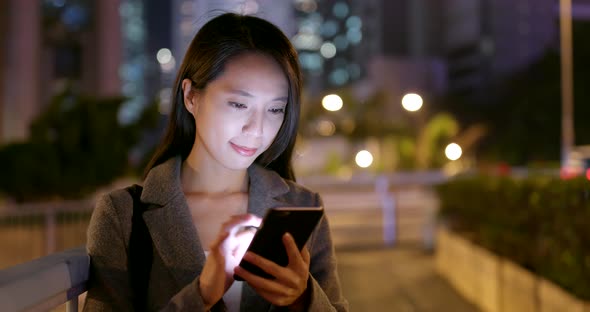 Young Business woman look at smart phone in city at night