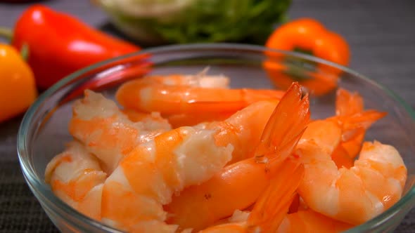 Hand Puts Delicious Shrimp in a Glass Bowl