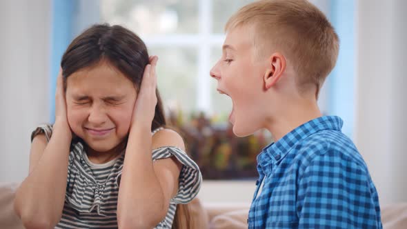 Irritated Girl Closing Ears with Hands While Brother Yelling at Her