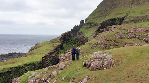 Aerial Back View of Unregnisable People Looking the Huge Cliffs in Faroe Islands Green Rocky