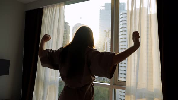 Silhouette of Woman Looking at Skyscrapers Outside Window