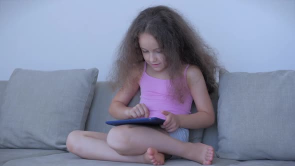 Curious Cute Girl Preschool Child Using a Digital Tablet Technology Device Looks telephone.Plays in