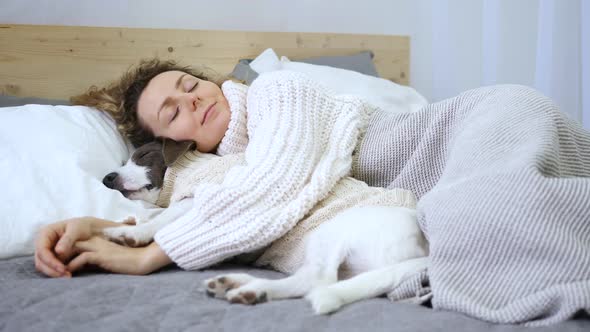 Fall Winter Cozy Concept. Woman Hugging Dog While Lying On Bed