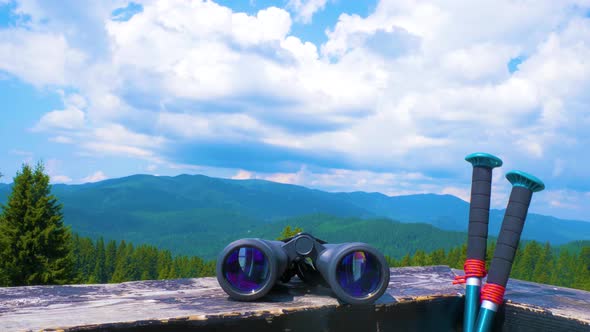 Hiking Sticks And Binoculars On The Wooden Table, Mountain Valley On A Background