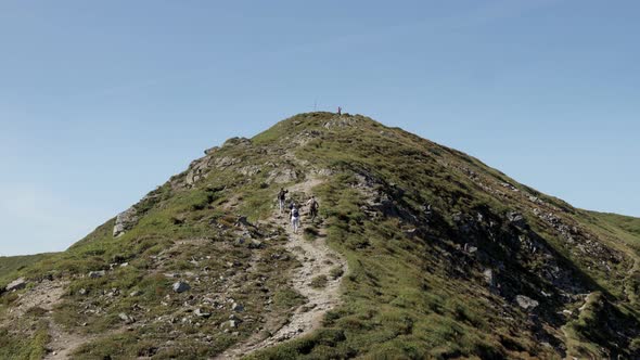 Hikers with backpacks climb to the top of the mountain. Hike to the top. Mountain landscape.