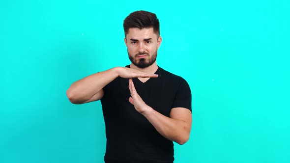 Young Caucasian Guy in a Black T-shirt Looking at the Camera, Showing the Stop Gesture with His Arms