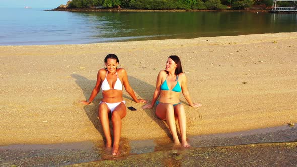 Girls best friends on marine coastline beach wildlife by transparent lagoon and white sandy backgrou