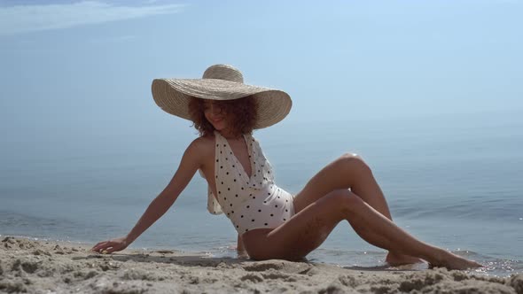 Elegant Girl Touching Sand Sitting Beach in Swimsuit