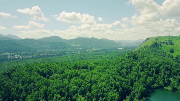 Aerial: Flying Over Mountains and Forest, Under Cloudy Sky. Also in Sight Is Mountain River