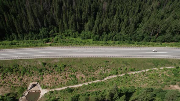 Aerial View of Scenic Road Between Green Trees with Pines on a Sunny Summer Morning