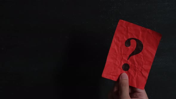 A man waving a red piece of paper with a question mark on it.