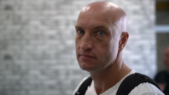 Portrait of Bald Man Turned and Looking at Camera with Frowning Expression Gaze