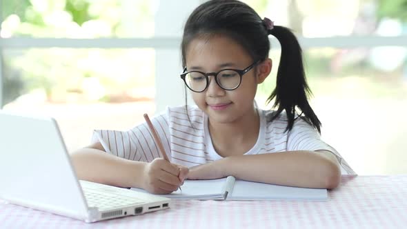 Beautiful Asian Girl Wear Glasses Writing To Notebook On The Table