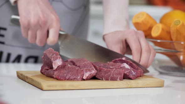 Woman Cutting Raw Meat on Small Pieces with Kitchen Knife Cutting Board. Female Cutting Red Beef