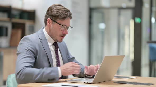 Businessman with Laptop Having Back Pain in Office 