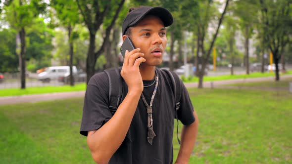 Student with Backpack Has Phone Conversation Outdoors