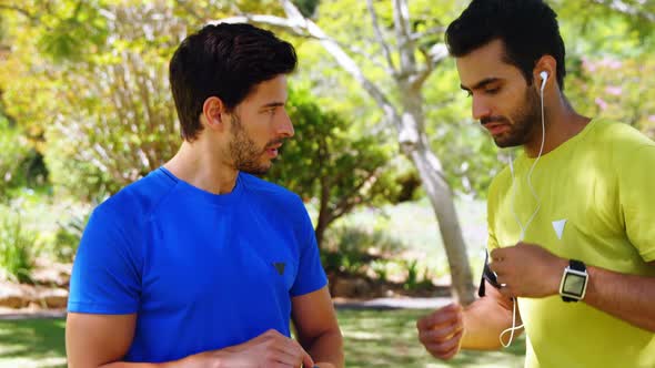 Two male joggers interacting with each other in park 4k