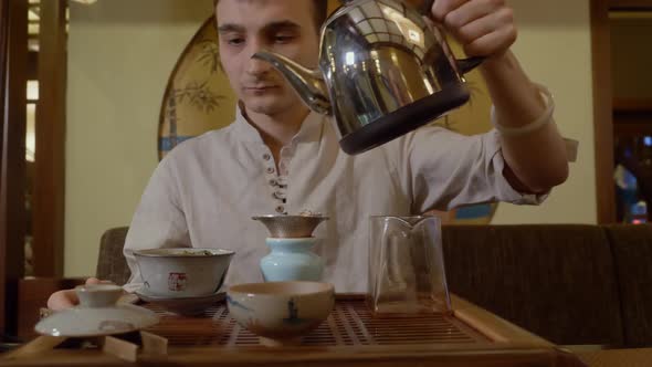 Tea Master Pouring Hot Water From Kettle in Gaiwan with Tea on Chinese Ceremony