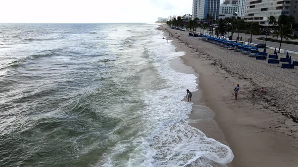 waver rolling on the beach two people looking at the sea, fort Lauderdale florida aerial view