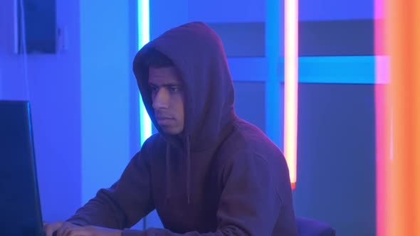 Close-up Shot of African Hacker Dressed in Hoodie Working on the Computer