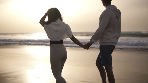 Relaxful Couple Walking Barefoot on the Beach