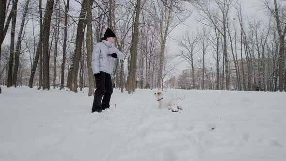 Happy Girl with Dog Running Along in Park Winter