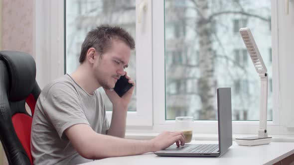 A young guy is talking on the phone, he is wearing a gray t-shirt