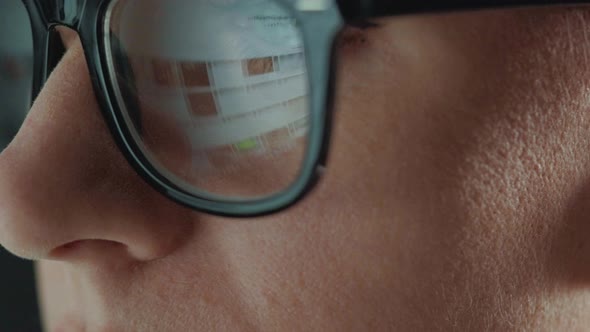 Woman in Glasses Looking on the Monitor and Surfing Internet. The Monitor Screen Is Reflected in the