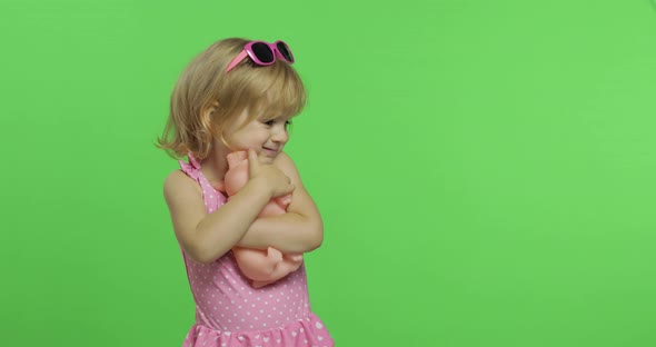 Child in Pink Swimsuit Playing with a Toy Pig. Chroma Key