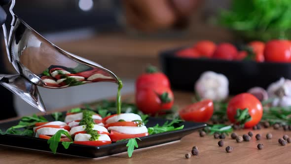 Caprese salad with tomatoes, mozzarella, basil, cheese, pesto sauce, fresh arugula leaves