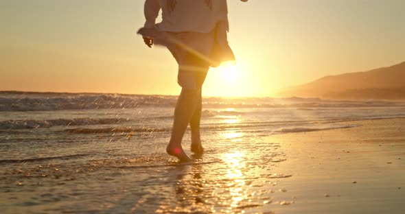 Slow Motion Woman Walking Barefoot in Ocean Waves in Golden Sunset Light. 
