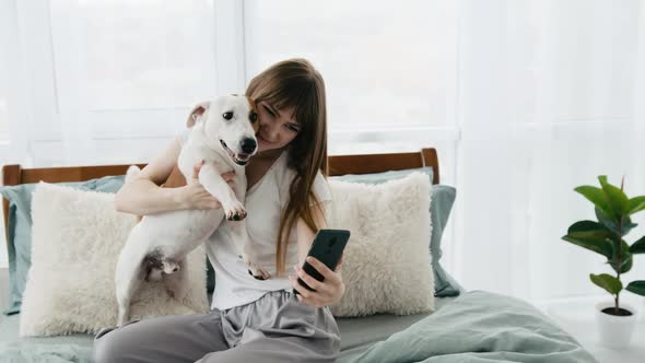 Girl with Dog and Phone in the Bed
