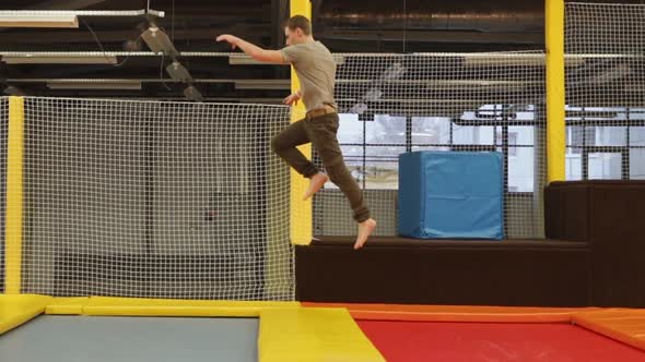 Male Acrobat Is Bouncing Through Few of Trampolines in a Gym